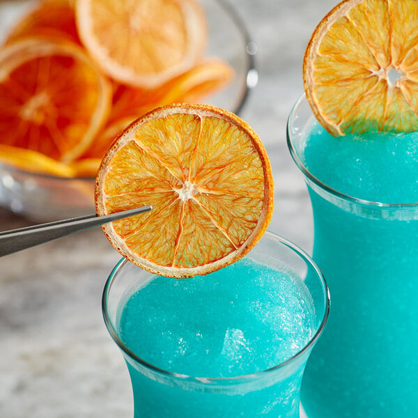 A blue drink with a Cocktail Garnish dried Cara Cara orange slice on top.