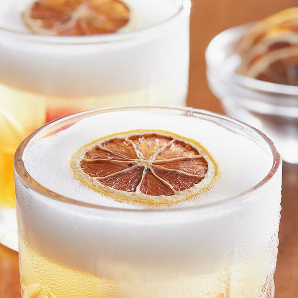 A close-up of a glass of lemonade with a dried lemon slice on the rim.