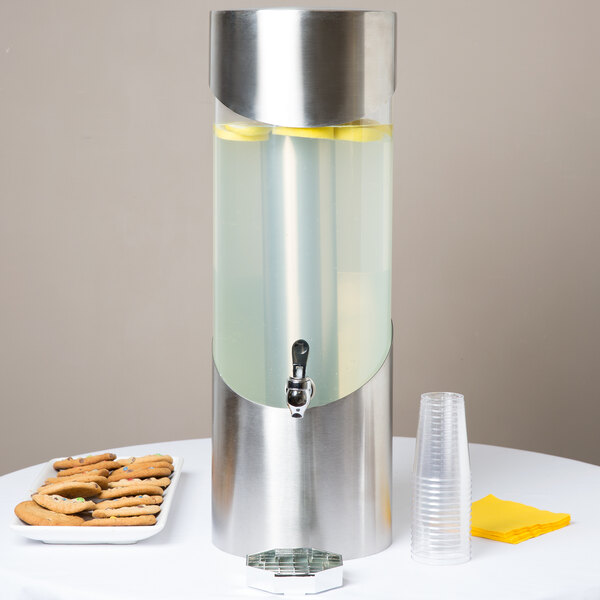 A silver and metal Cal-Mil beverage dispenser with cookies on a table.