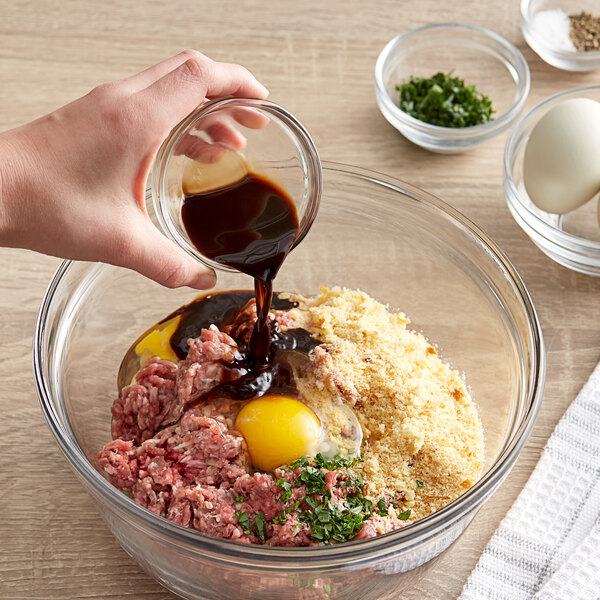 A person pouring French's Worcestershire Sauce into a bowl of food.