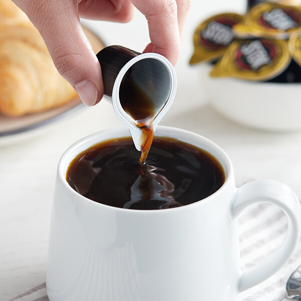 A person pouring Stok espresso coffee into a cup of coffee.