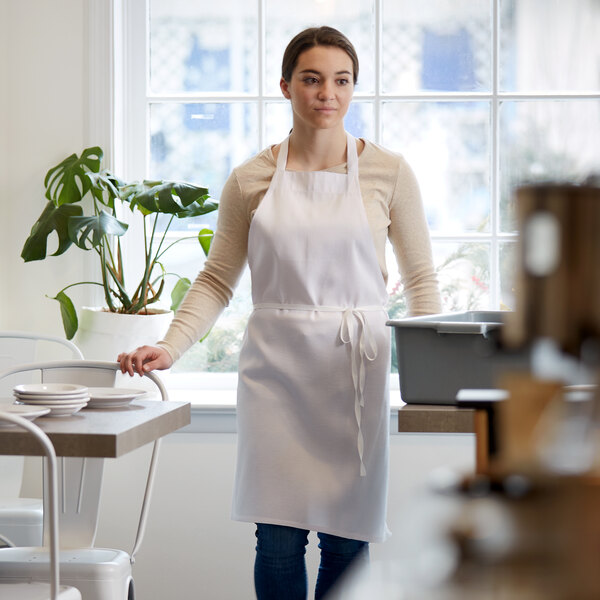 A woman in a white Choice apron standing in a professional kitchen.