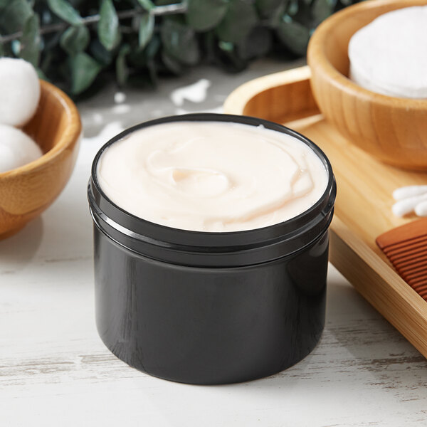 A black jar of cream on a white tray.