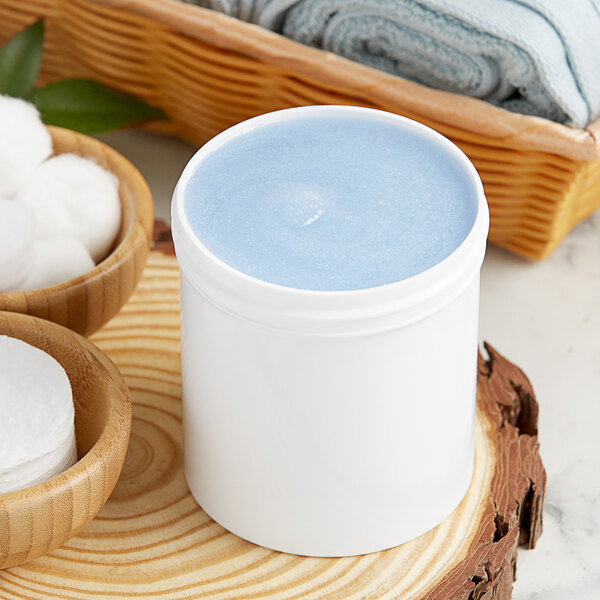 A white plastic jar filled with blue liquid on a wood surface.