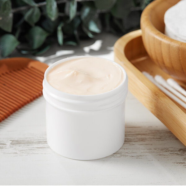 A white 2 oz. jar of cream on a wooden surface.