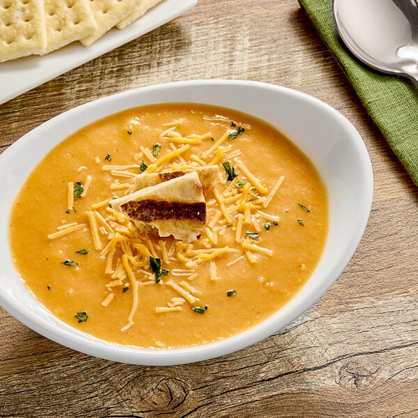 A bowl of Chef Francisco Cheesy Chicken Tortilla Soup with crackers and cheese.