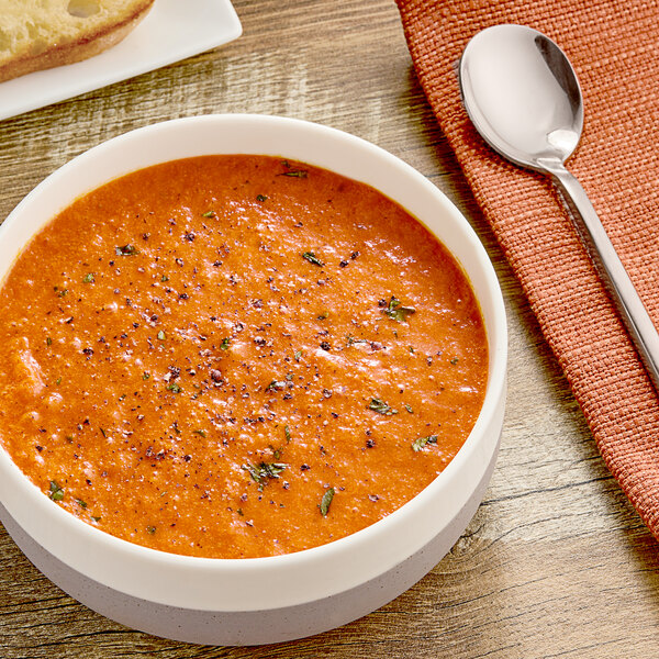 A bowl of TrueSoups Old Fashioned Creamy Tomato Soup on a table with a spoon.