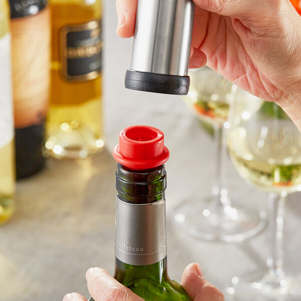 A hand using an Acopa red wine saver to seal a bottle of wine.