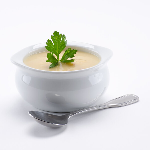 A bowl of Silver Skillet cream of chicken soup with a silver spoon and a sprig of parsley on top.