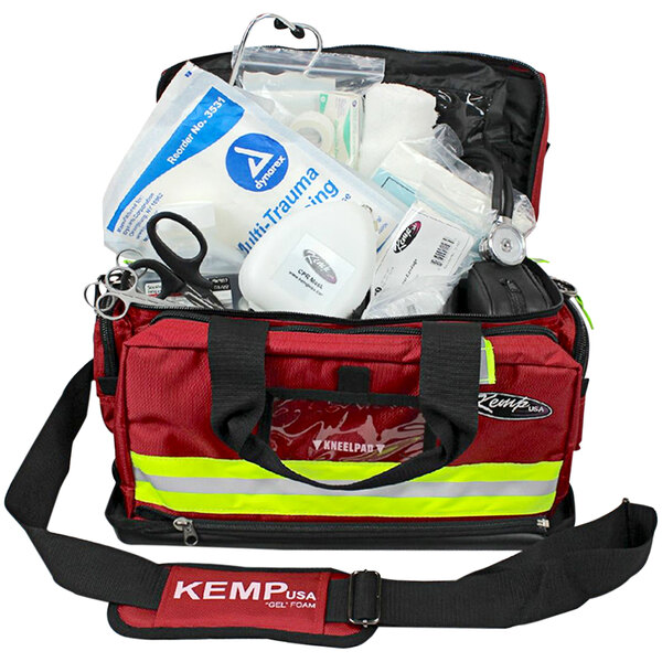 A red Kemp USA medical bag with white and yellow labels filled with first aid supplies.