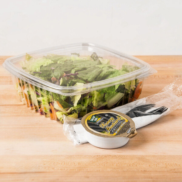 A salad in a Genpak clear plastic deli container on a table.