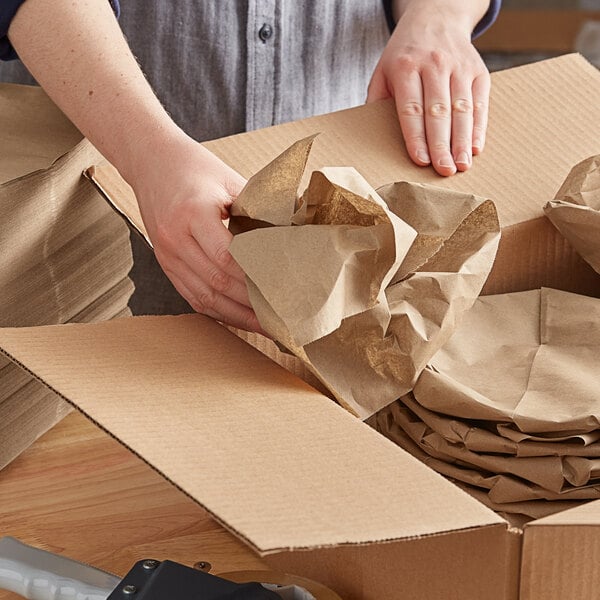 A person packing a box with Pregis Quantum fanfold brown paper.
