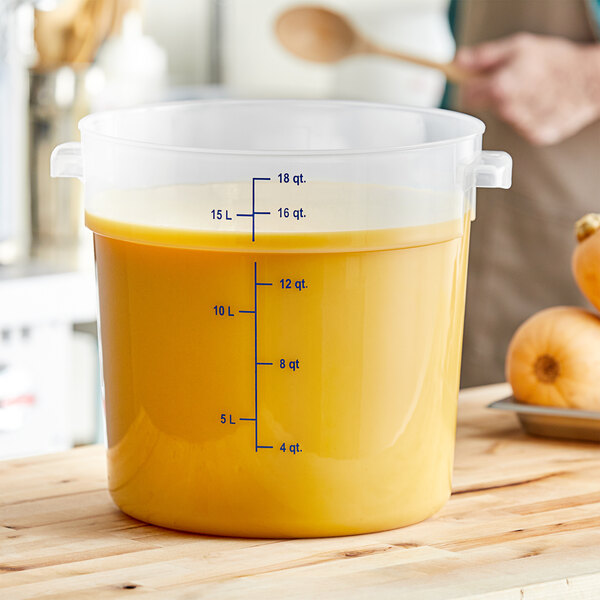 A close up of a Carlisle translucent round food storage container with yellow liquid inside.