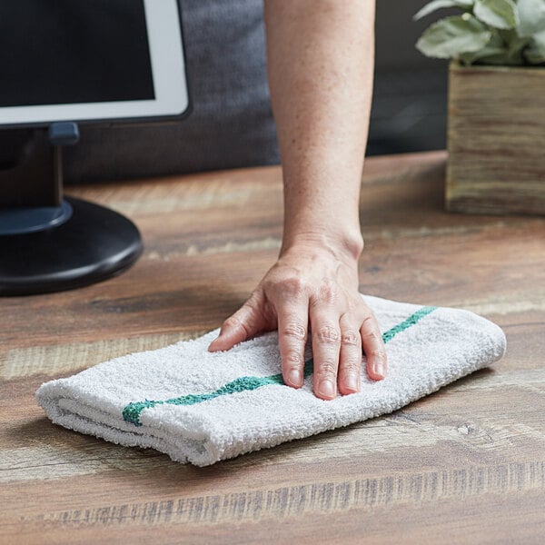 A hand on a green and white striped terry bar towel.