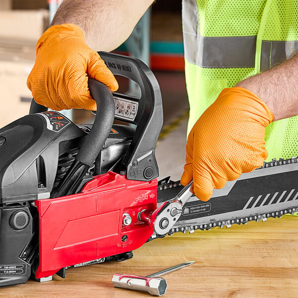 A person wearing Lavex Pro nitrile gloves holding a chainsaw.