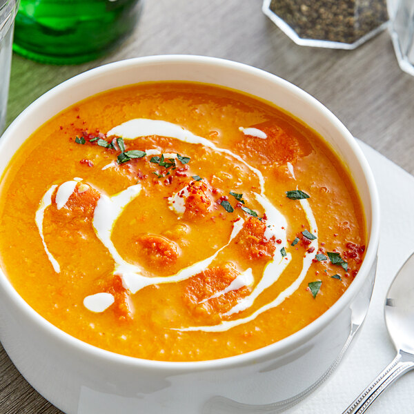 A bowl of Kettle Collection Carrot Ginger Soup with a spoon.