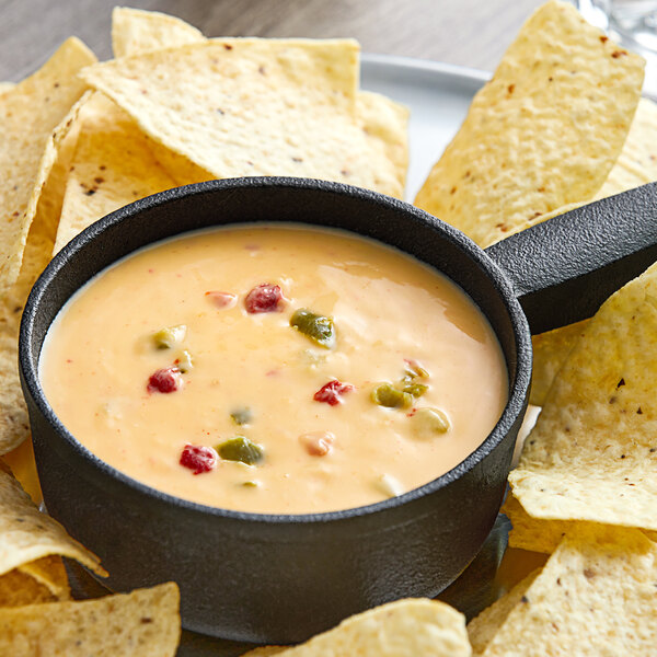 A bowl of Kettle Collection Golden Queso cheese dip next to tortilla chips.