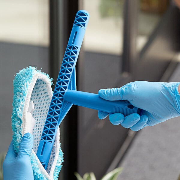 A person in blue gloves using a Lavex 14" T-Bar Handle to clean a window.