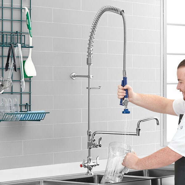 A man using a Waterloo pre-rinse faucet with a double-jointed add-on faucet to fill a glass of water.