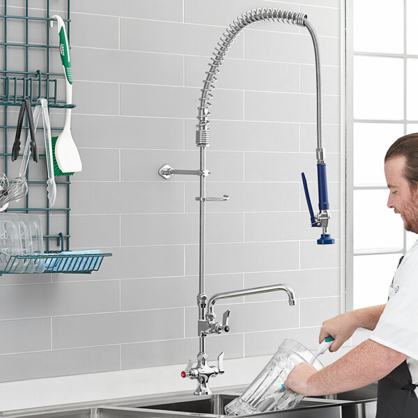 A man using a Waterloo pre-rinse faucet to wash dishes in a sink.