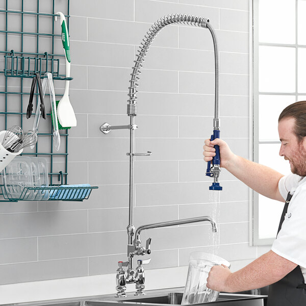 A man using a Waterloo pre-rinse faucet to wash dishes in a professional kitchen.