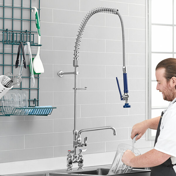 A man using a Waterloo pre-rinse faucet to wash dishes on a counter in a professional kitchen.