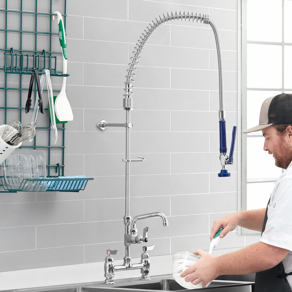 A man using a Waterloo deck-mounted pre-rinse faucet to wash dishes in a professional kitchen.
