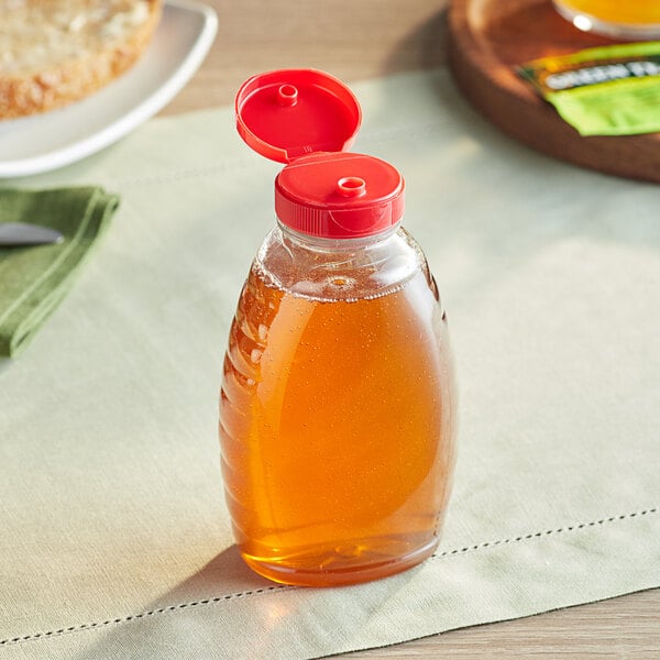 A Classic Queenline PET honey bottle with honey on a table.