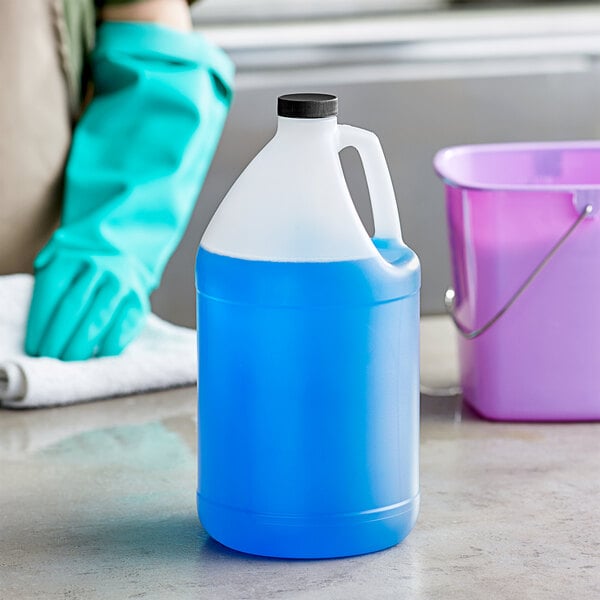 A translucent HDPE gallon jug of blue liquid with a black cap sitting on a counter.
