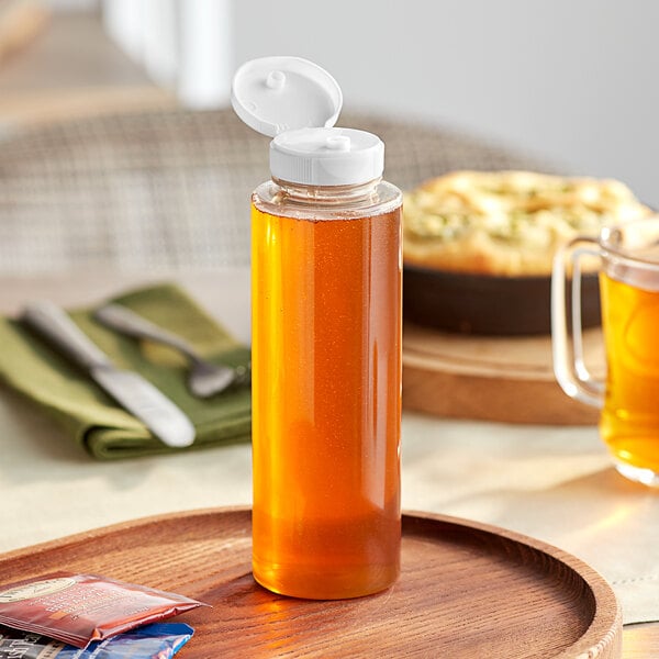 A clear PET sauce bottle with a white cap on a tray.