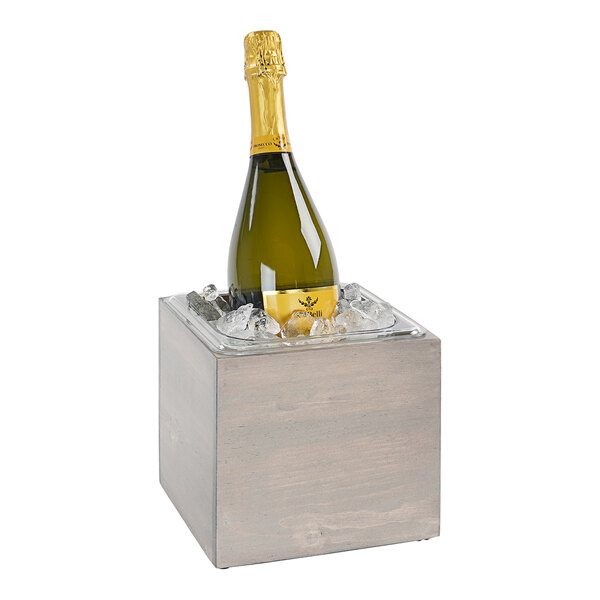 A bottle of champagne in a Cal-Mil gray pine ice housing on a table.