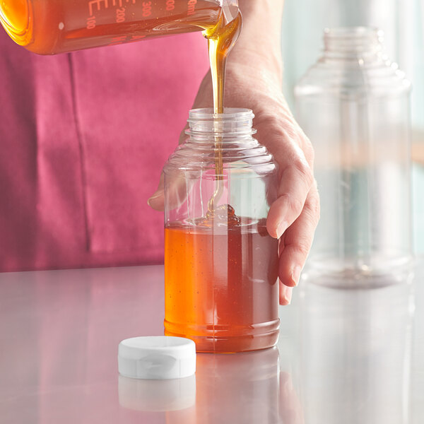 A person pouring honey into a container.
