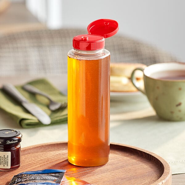 A close-up of a clear PET sauce bottle with a red cap on a tray.