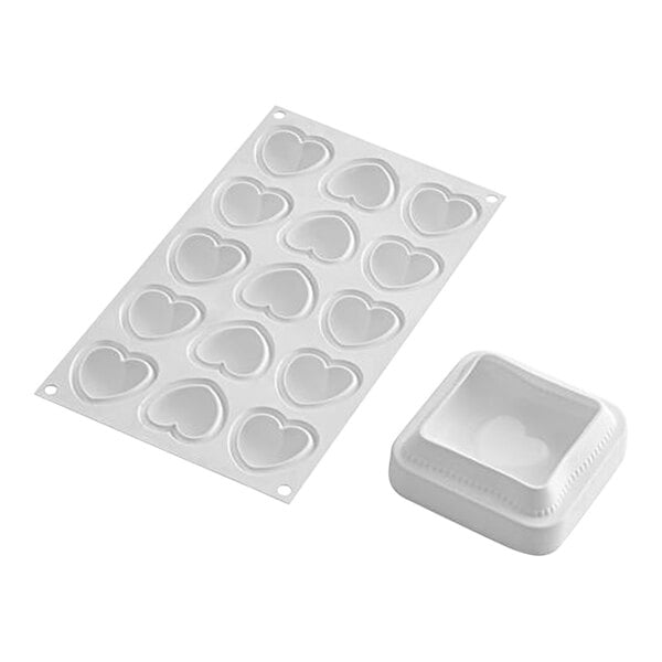 A white heart shaped silicone mold in a white square container.