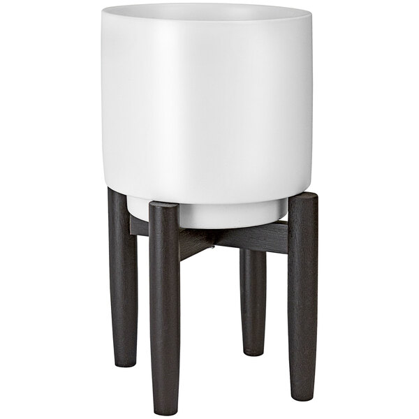 A white ceramic plant stand with black legs holding a white pot.