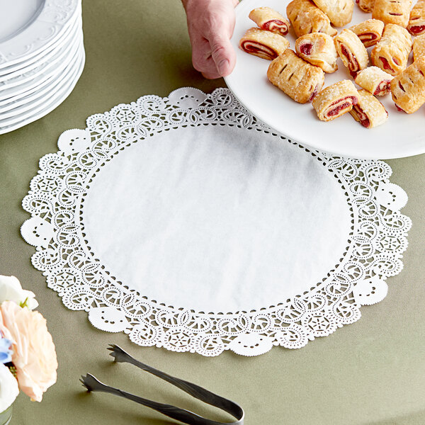 A hand holding a plate of pastries with a Lace Normandy doily on it.