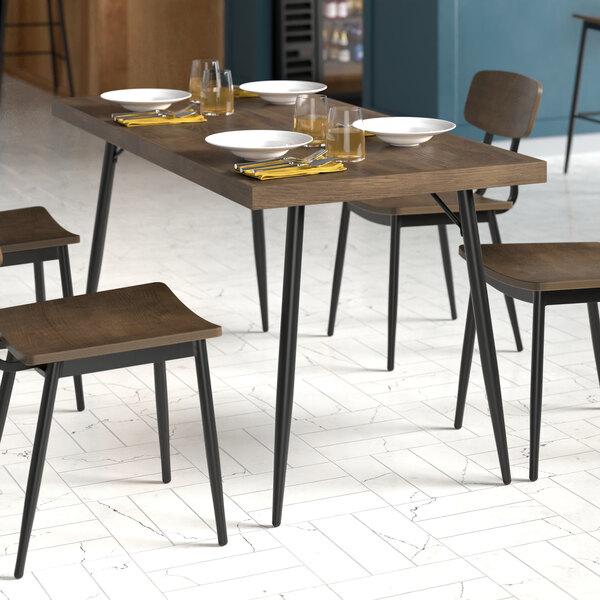 A Lancaster Table & Seating butcher block table with chairs, plates, and glasses on it.