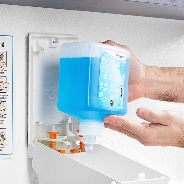A person's hands holding a blue liquid container of SC Johnson Professional Azure Foaming Hand Soap.