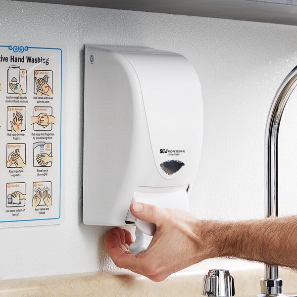 A person using a SC Johnson Professional Proline Curve 1 liter white manual soap dispenser.