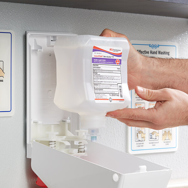 A person's hands using SC Johnson Professional InstantFOAM PURE hand sanitizer refill at a dispenser.
