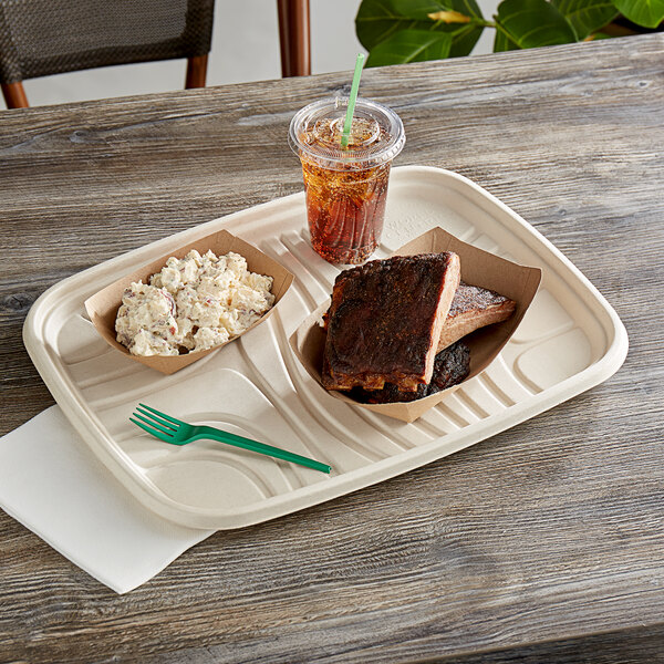A World Centric compostable fiber serving tray with a bowl of potato salad, a plastic cup with a straw, and a plate of food on a table.