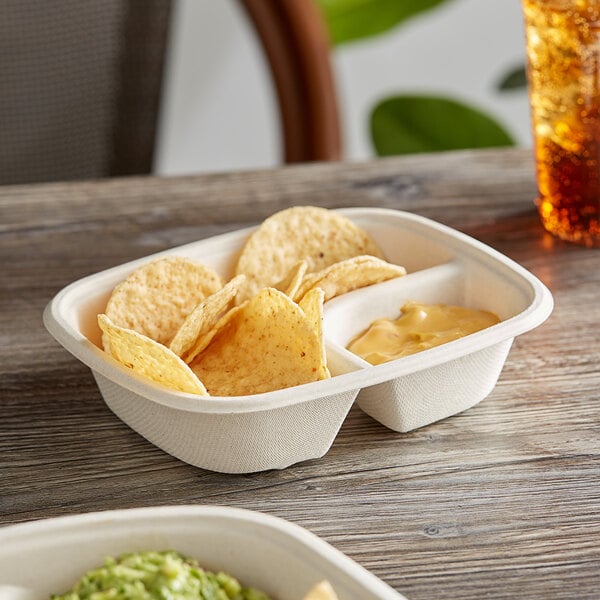 A white World Centric compostable paper tray with chips and dips on a table.