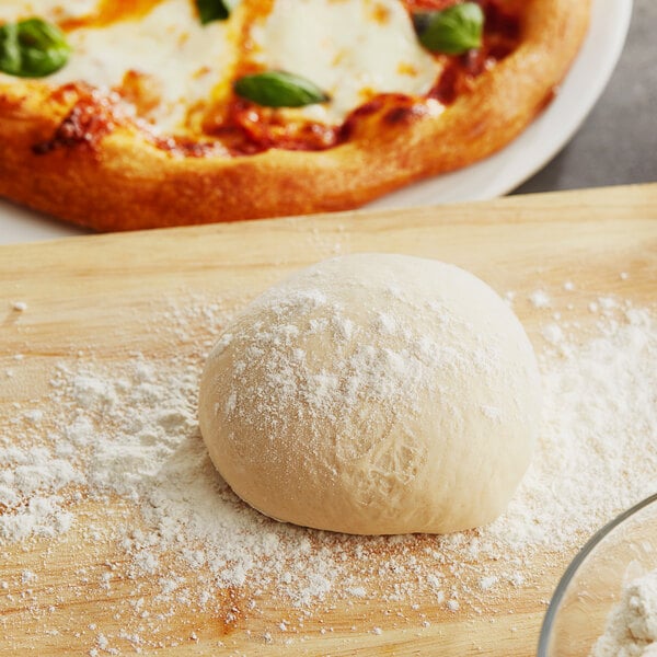 A ball of King Arthur pizza dough with flour on it.
