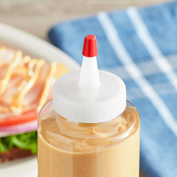 A bottle of mustard with a 38/400 natural Yorker spout cap on a table in a deli.