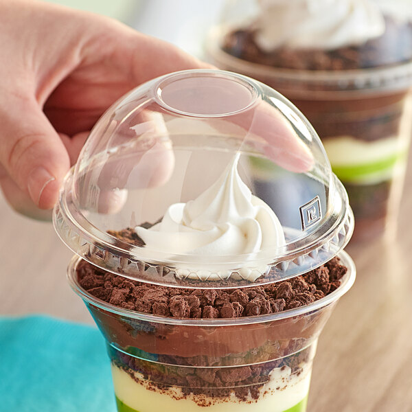 A hand holding a World Centric plastic cup with a dessert inside.