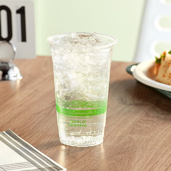 A World Centric compostable plastic cup with ice on a table.
