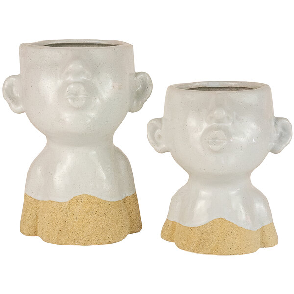 A pair of white ceramic vases with faces on them.