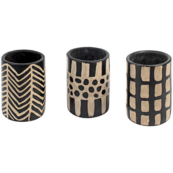A group of three black and white clay cylinder vases with designs.