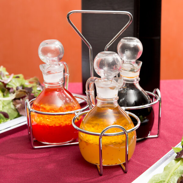 A Thunder Group wire condiment jar holder with glass containers of liquid in it.