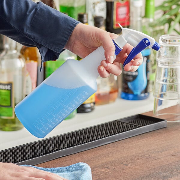 A person holding a Lavex blue plastic spray bottle over a blue cloth.